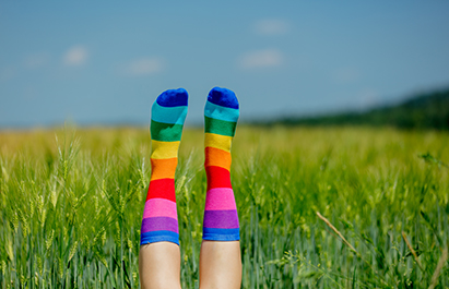 female legs in LGBT socks raised up on a wheat field
